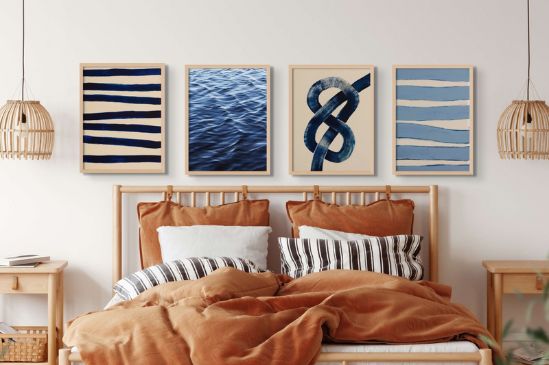 set of four modern coastal bedroom art prints above wooden bed. The bed frame is wooden and the bedding is a burnt orange - framed bedroom wall art