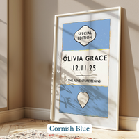 Personalised baby name print - Framed artwork with 'Olivia Grace' and a date on a blue background, leaning against a wall.
