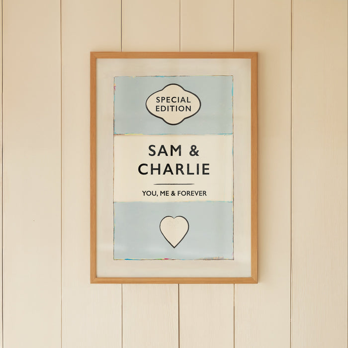 Framed artwork on a wall with a wicker chair and small table below.