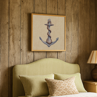 Green striped bed with decorative pillows against a wooden wall with an anchor painting.