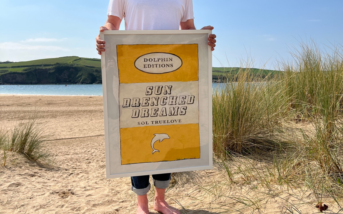 framed book art print being photographed on beach - beach art print on beach in cornwall
