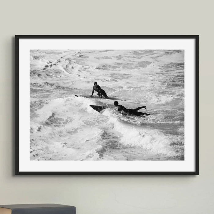 black & white photograph of two surfers in the surf in a black frame above a desk - beach house art