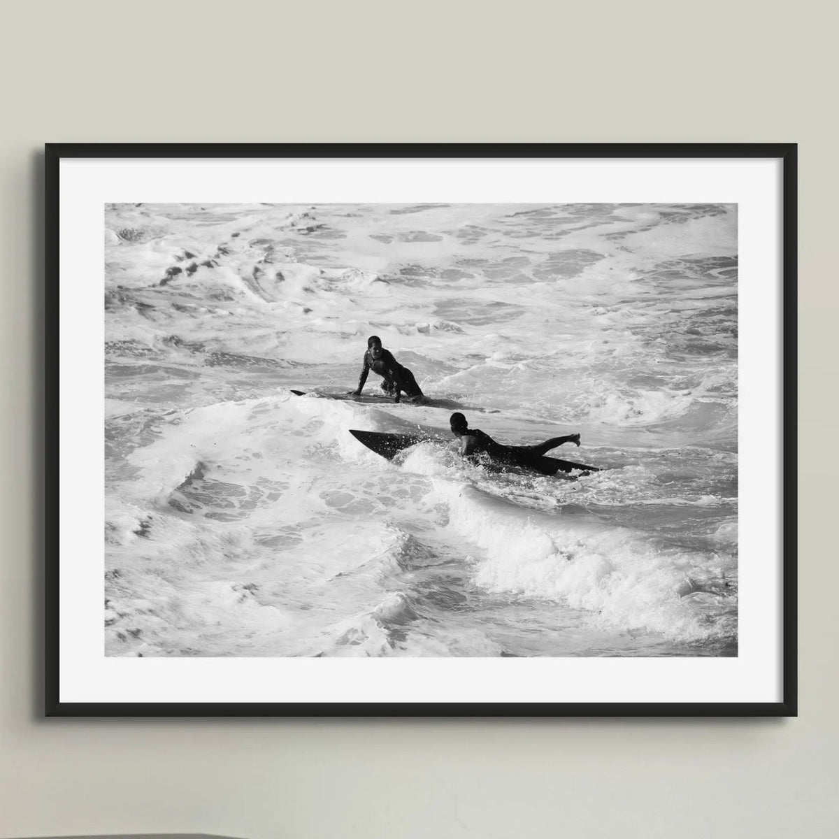 black & white beach art photograph of two surfers in the waves in a black frame above a tidy desk - beach house art