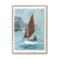 Framed artwork of a sailboat with a red sail on a blue sea with cliffs in the background.