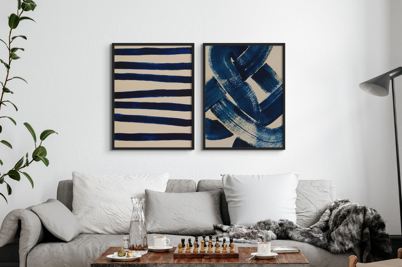 set of two framed blue art prints above grey sofa in a living room. the art has black frames and is abstract line art