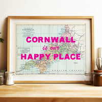 Framed map of Cornwall with 'Cornwall is our happy place' text on a wooden surface.