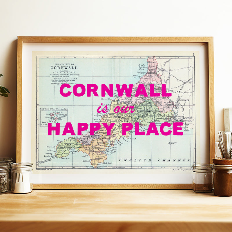 Framed map of Cornwall with 'Cornwall is our happy place' text on a wooden surface.