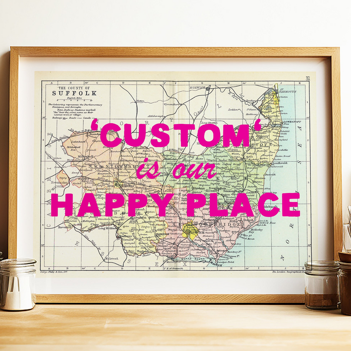 Framed map with 'Custom is our Happy Place' text on a wooden surface.