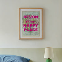 Bedroom with a framed map reading 'Devon is our happy place' above a bed.