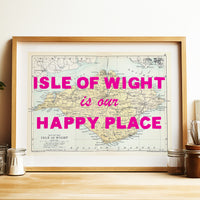Framed map of the Isle of Wight with pink text on a wooden surface.
