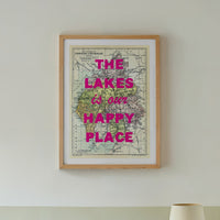 Framed map with 'The Lakes is our happy place' text above a bed in a bedroom.