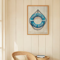 Framed artwork with motivational quote on a wall above a wicker chair in a bright room.