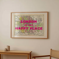 Framed map with 'London is our happy place' text above a wooden table and chair.