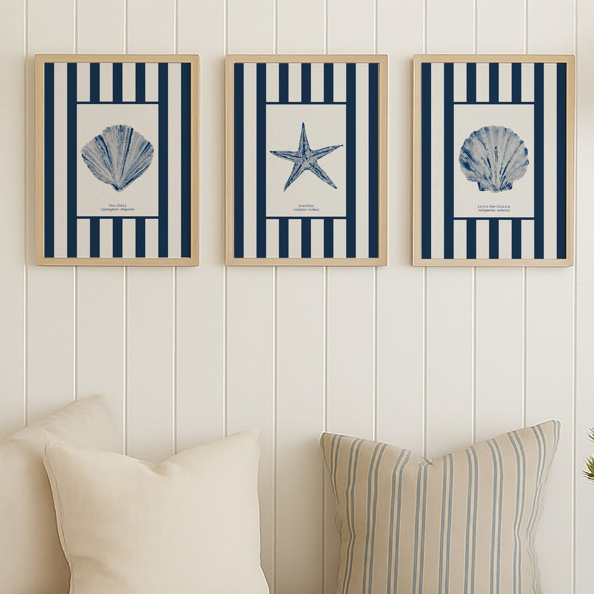 Three framed coastal-themed prints above a sofa with decorative pillows and a blanket.