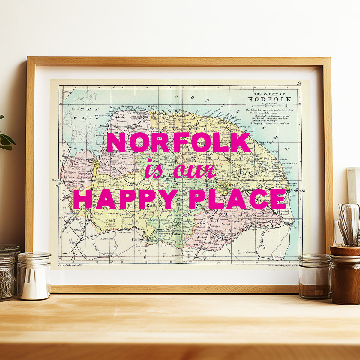 Framed map of Norfolk with 'Norfolk is our happy place' text on a wooden surface.