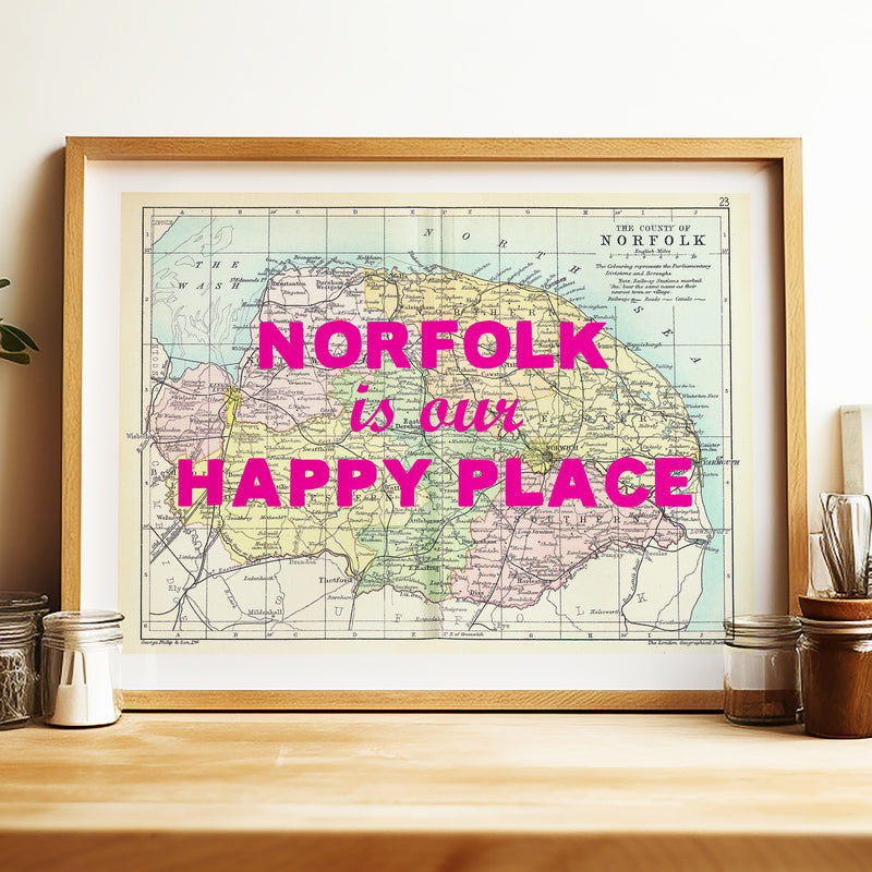 Framed map of Norfolk with 'Norfolk is our happy place' text on a wooden surface.