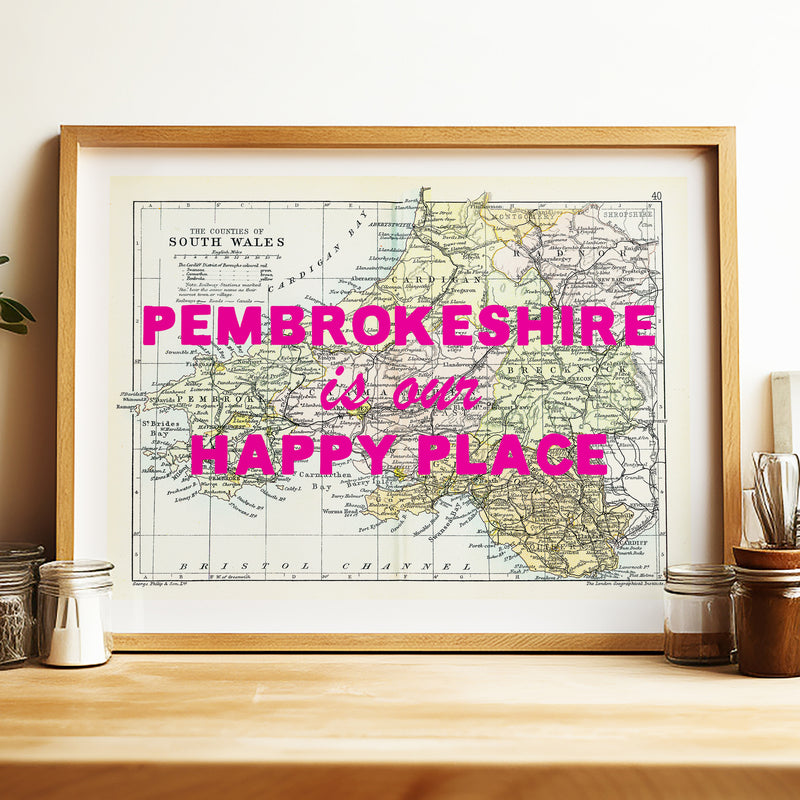 Framed map of Pembroke with 'Pembrokeshire is our happy place' text on a wooden shelf.