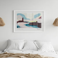 A framed abstract landscape art print of Porthleven in Cornwall hangs on a white wall above a neatly made bed with white pillows and a beige blanket. The print features soft pastel blocks of blue, pink, brown, and cream, and is flanked by two woven pendant lights.