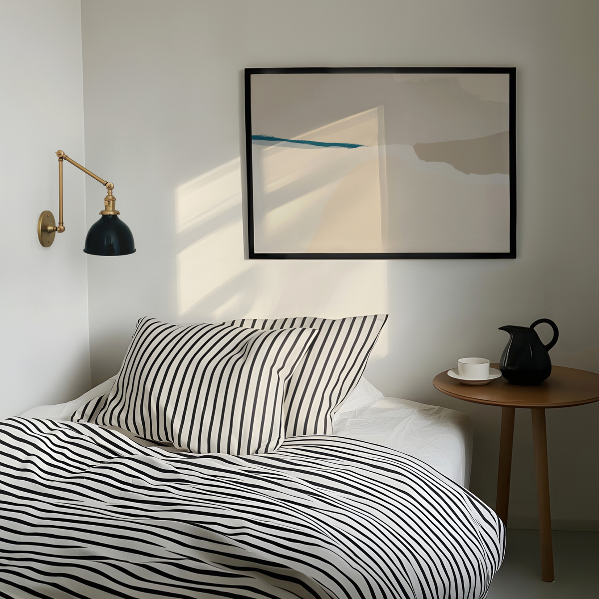 Modern bedroom with striped bedding, wall lamp, and abstract art.