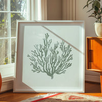 Sage green coral art print in natural wood frame styled in a bright coastal interior