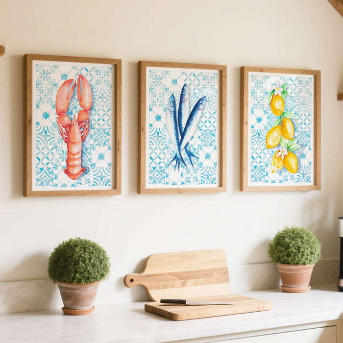 Set of 3 food painting in kitchen - framed kitchen art prints. Kitchen with white cabinets, a coffee maker, and decorative kitchen wall art of lobster, fish and lemons on wall.
