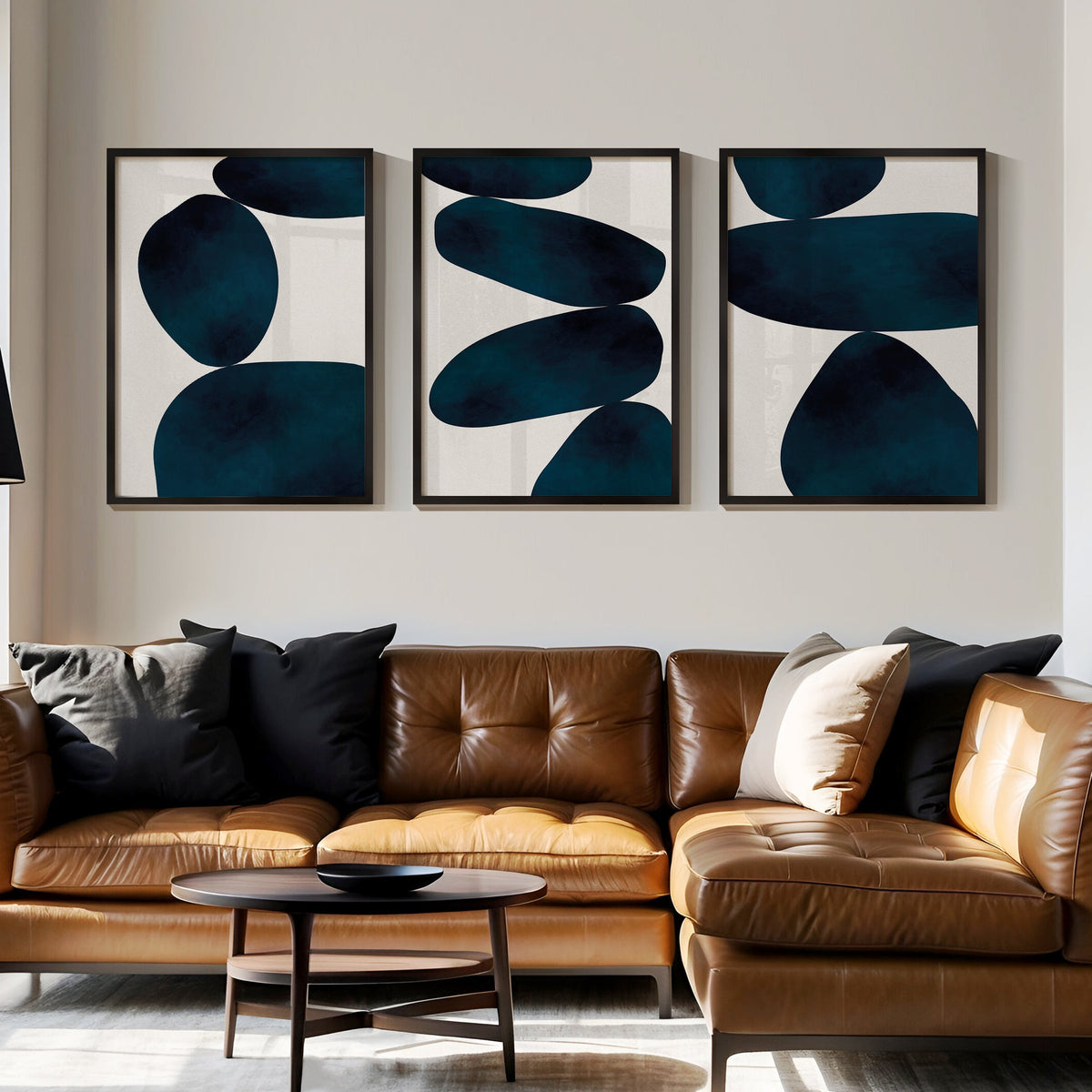 Set of 3 abstract framed art prints in living room. Modern living room with a brown leather sofa, abstract art, and a lamp.