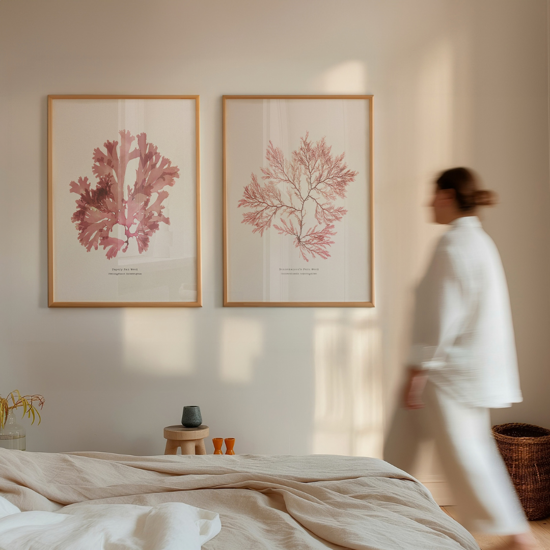 Set of two pressed seaweed prints in bedroom with woman walking.