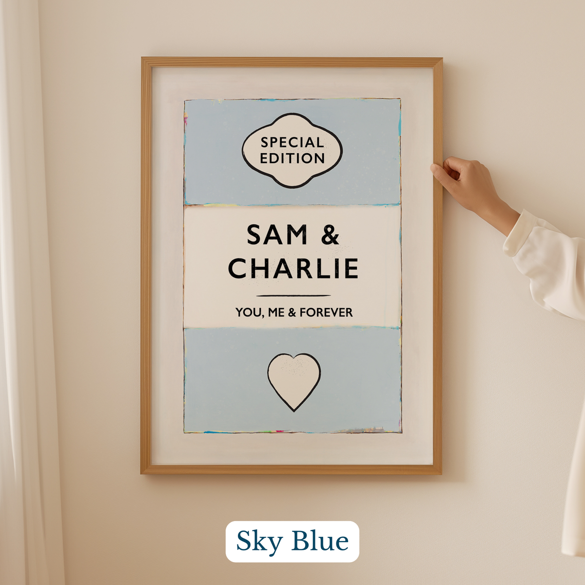 Personalised wedding/engagement print. Couple Print. Framed artwork with 'Sam & Charlie' text and heart symbol on a light blue background, held by a hand.
