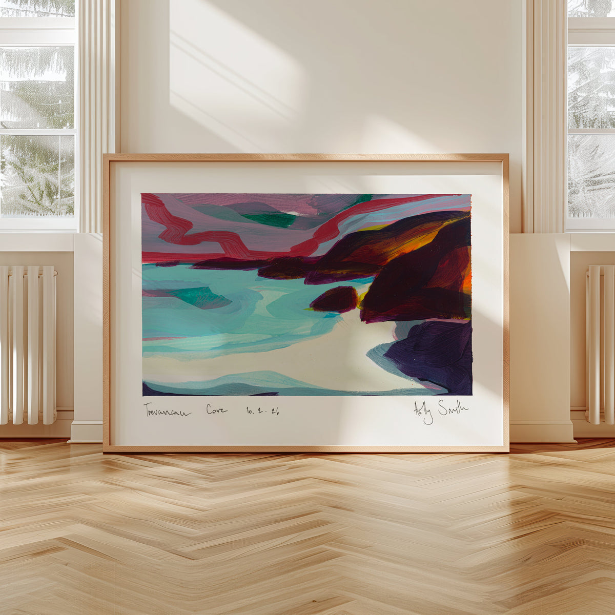 A framed abstract landscape painting leaning against a wall in a bright room with large windows and light wood flooring. The artwork features swirling teal, pink, purple, orange, and dark blue tones, enclosed in a light wood frame.