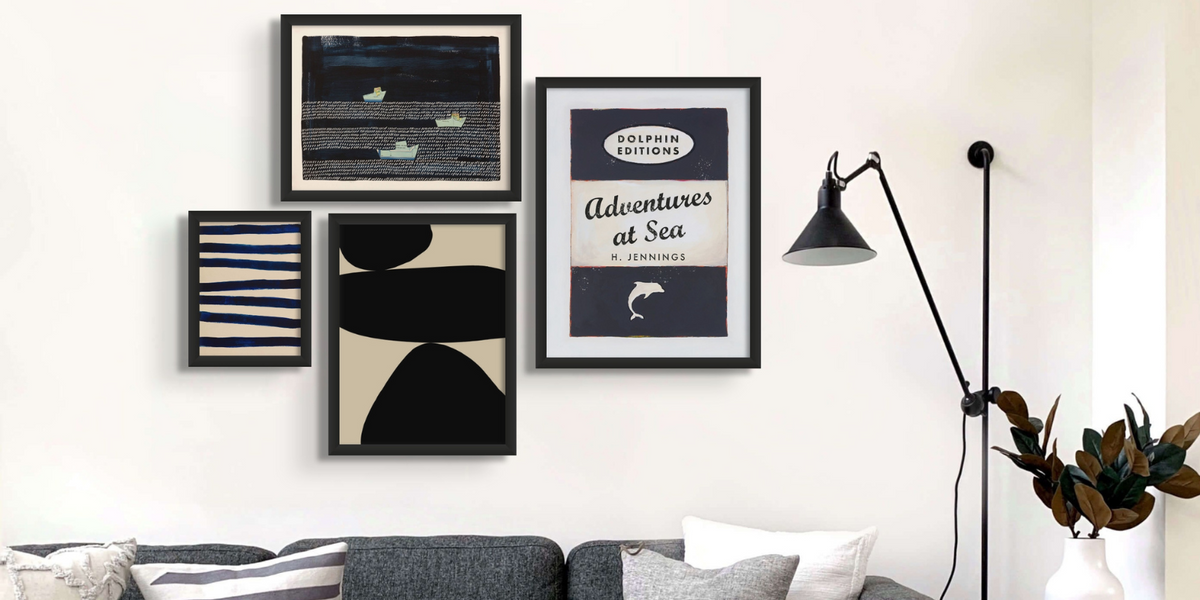 a selection of coastal wall art in a gallery wall in a living room above a sofa.