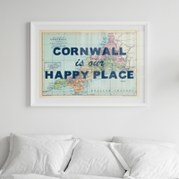 Framed map of Cornwall with 'Cornwall is our happy place' text above a bed.