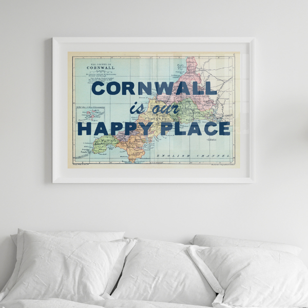 Framed map of Cornwall with 'Cornwall is our happy place' text above a bed.
