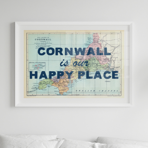 Framed map print of Cornwall with 'Cornwall is our happy place' text on a white wall.