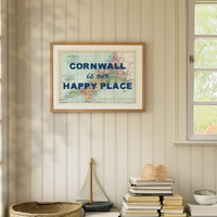 Framed map of Cornwall with 'Cornwall is our happy place' text on a wall with decorative items below.