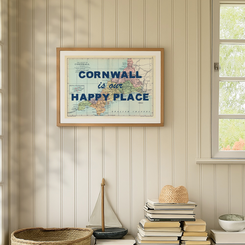 Framed map of Cornwall with 'Cornwall is our happy place' text on a wall with decorative items below.