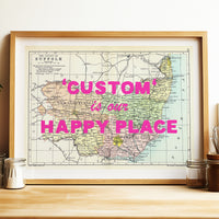 Framed map with 'Custom is our Happy Place' text on a wooden surface