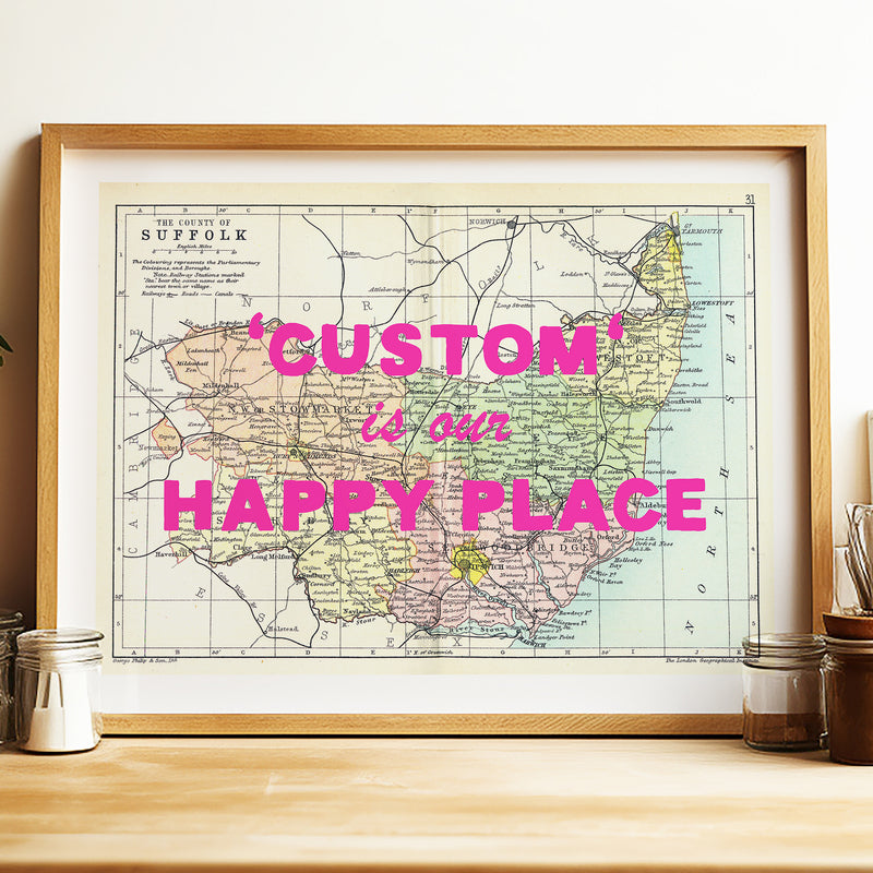 Framed map with 'Custom is our Happy Place' text on a wooden surface