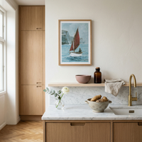 Modern kitchen with wooden cabinets, marble countertop, and framed fishing boat artwork on the wall.