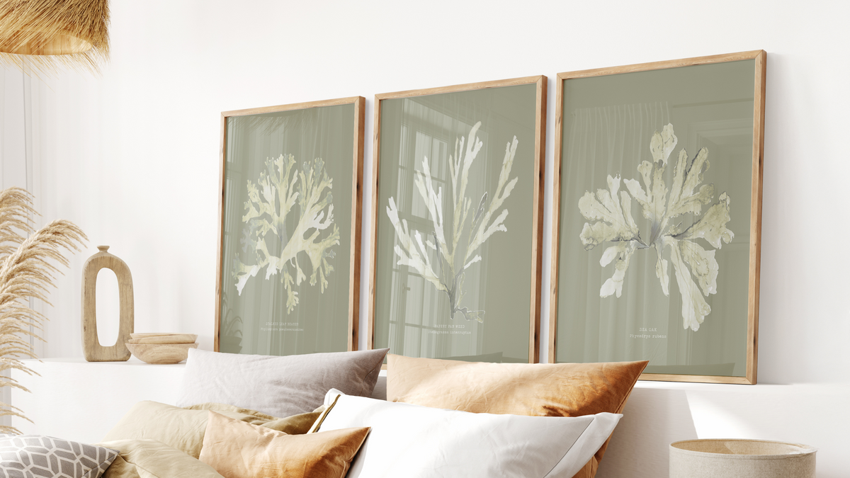 set of three olive green art prints framed on wall behind bed - green wall art