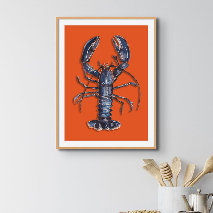 framed lobster art print on wall in kitchen, with orange background.