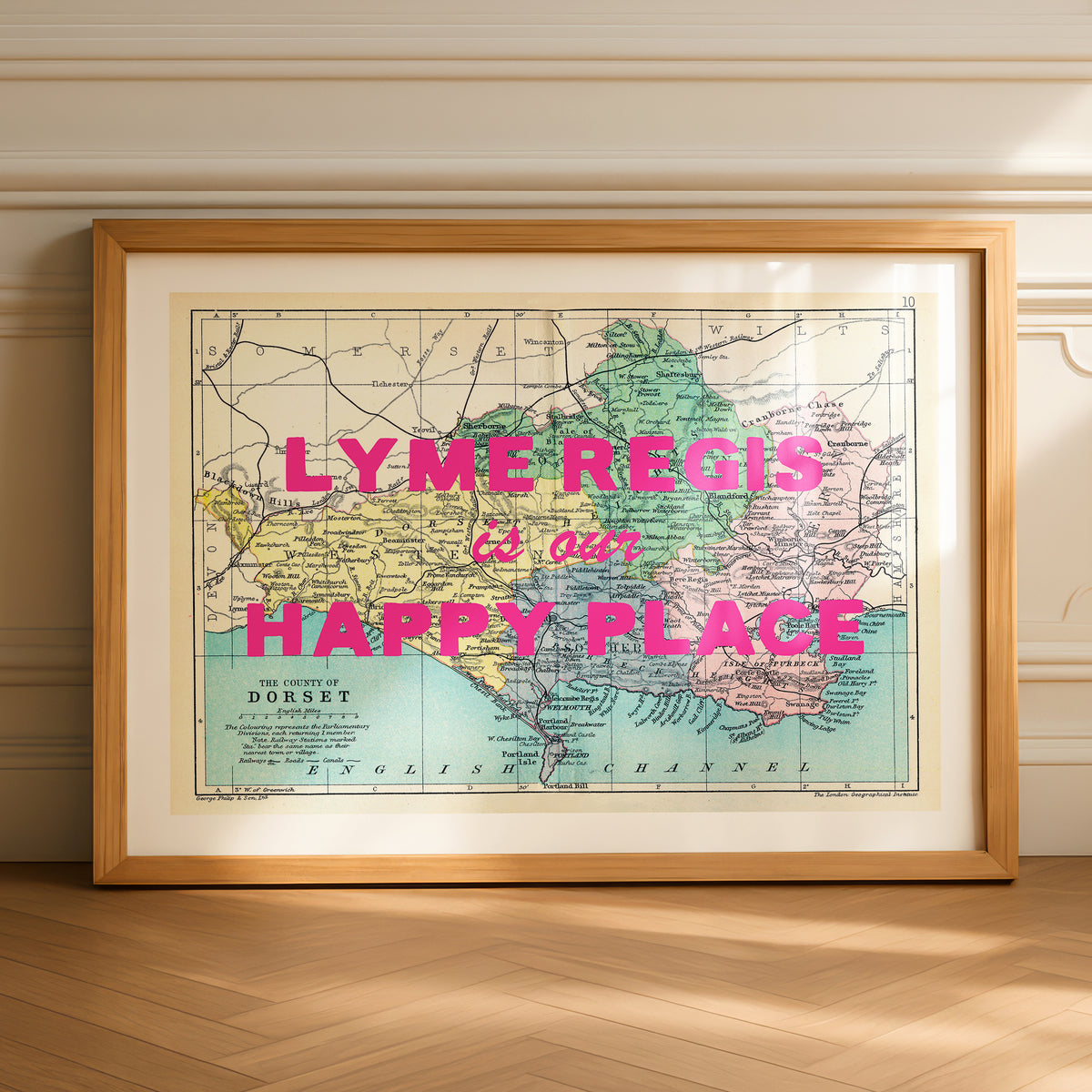Framed map with 'LYME REGIS is our HAPPY PLACE' text on a wooden floor.
