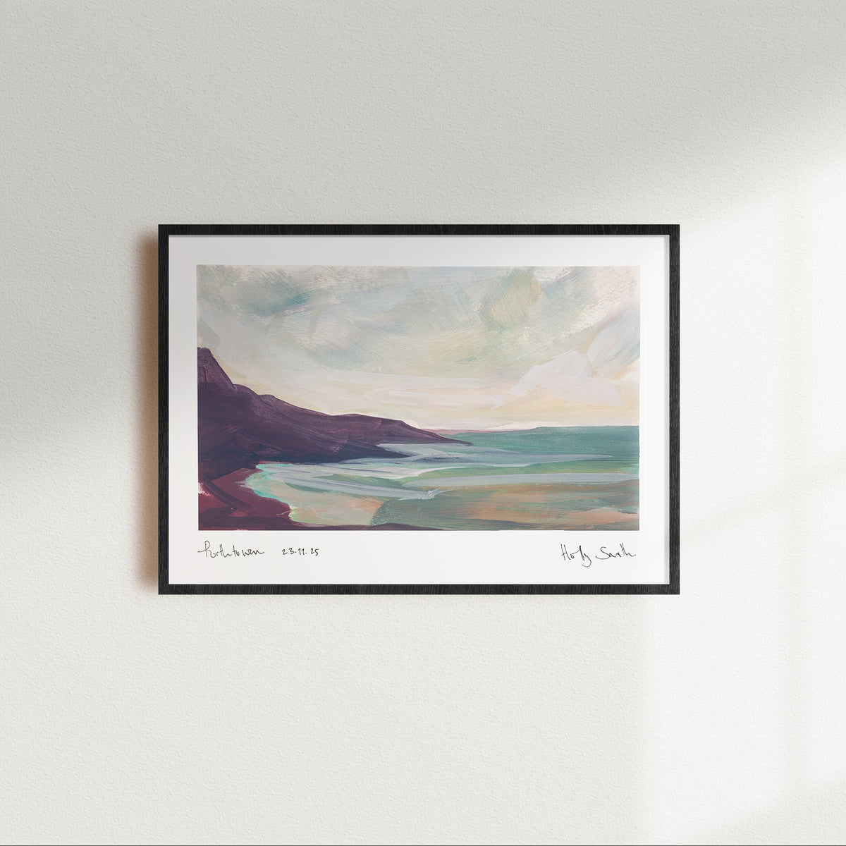 A framed landscape art print of Porthtowan in Cornwall featuring an impressionistic painting of a coastal scene with dark cliffs, turquoise water, and a cloudy sky, shown against a plain white background.