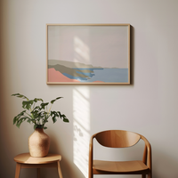 Abstract framed artwork on a wall with a plant and wooden chair below.