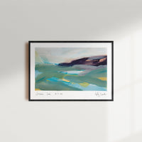 A framed abstract landscape painting of Sennen Cove in Cornwall, featuring teal, green, blue, and dark purple brushstrokes on a white mat with a black frame. A framed abstract landscape art print with a black frame and white mat, hanging on a light grey wall with soft window shadows.