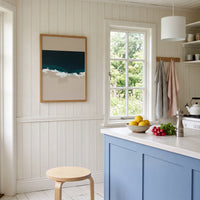 Kitchen interior with blue cabinets, white countertop, and framed abstract artwork on the wall.