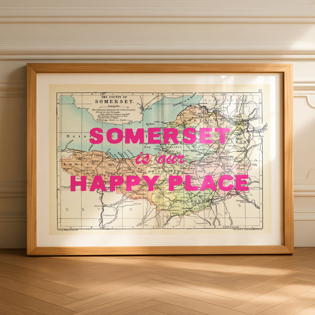 Framed map of Somerset with 'Somerset is our happy place' text on a wooden floor.