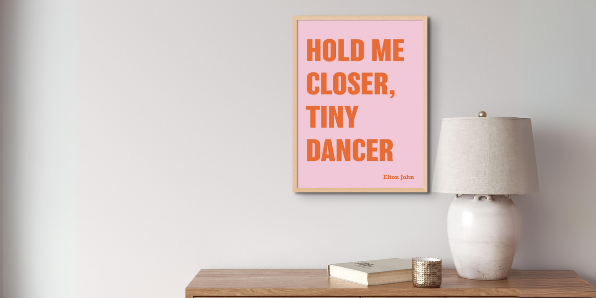 framed song lyric art print 'hold me closer tiny dancer' song print on wall above table.