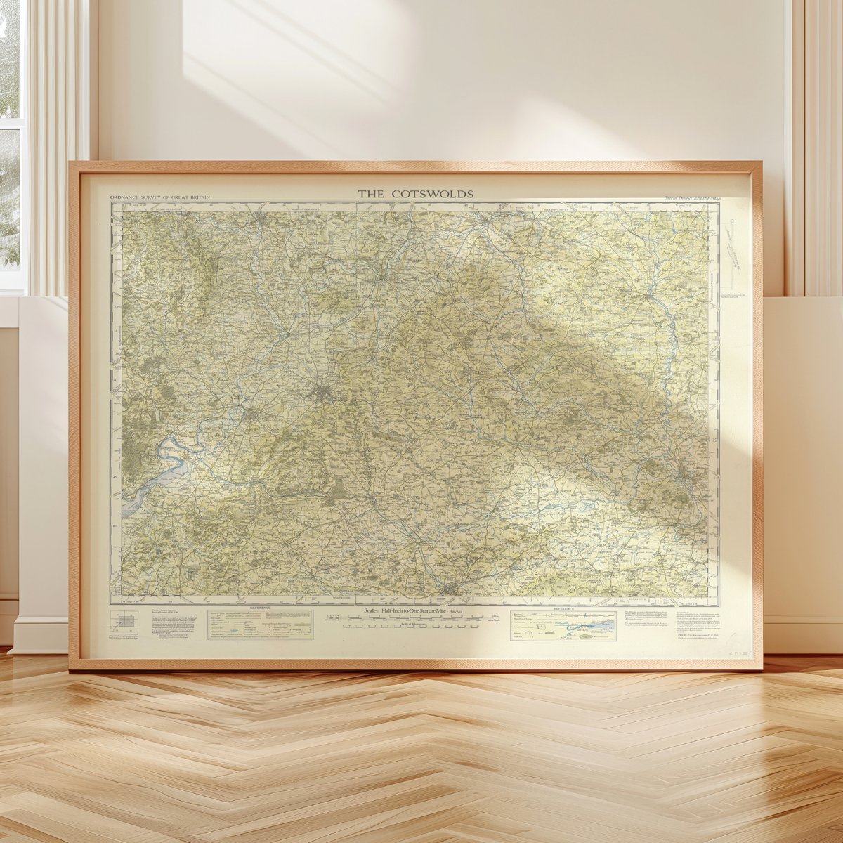 Framed vintage map print of The Cotswolds on a wooden floor with a neutral wall background