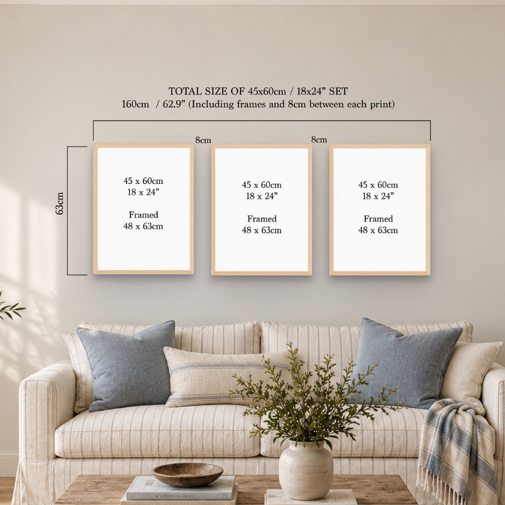 Three framed art prints displayed on a beige wall above a sofa, with overlaid dimension labels showing the total size of a 45x60cm / 18x24" set. The scene is styled as a living room with a striped sofa, pillows, and a vase with greenery.
