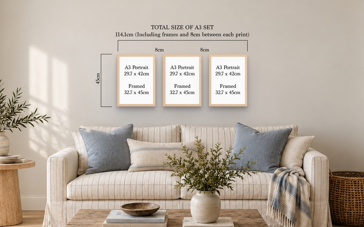 A living room scene showing a sofa with pillows and decor, with overlaid dimension labels for a set of three A3 portrait prints: 8 cm by 8 cm each, totaling 114.3 cm.